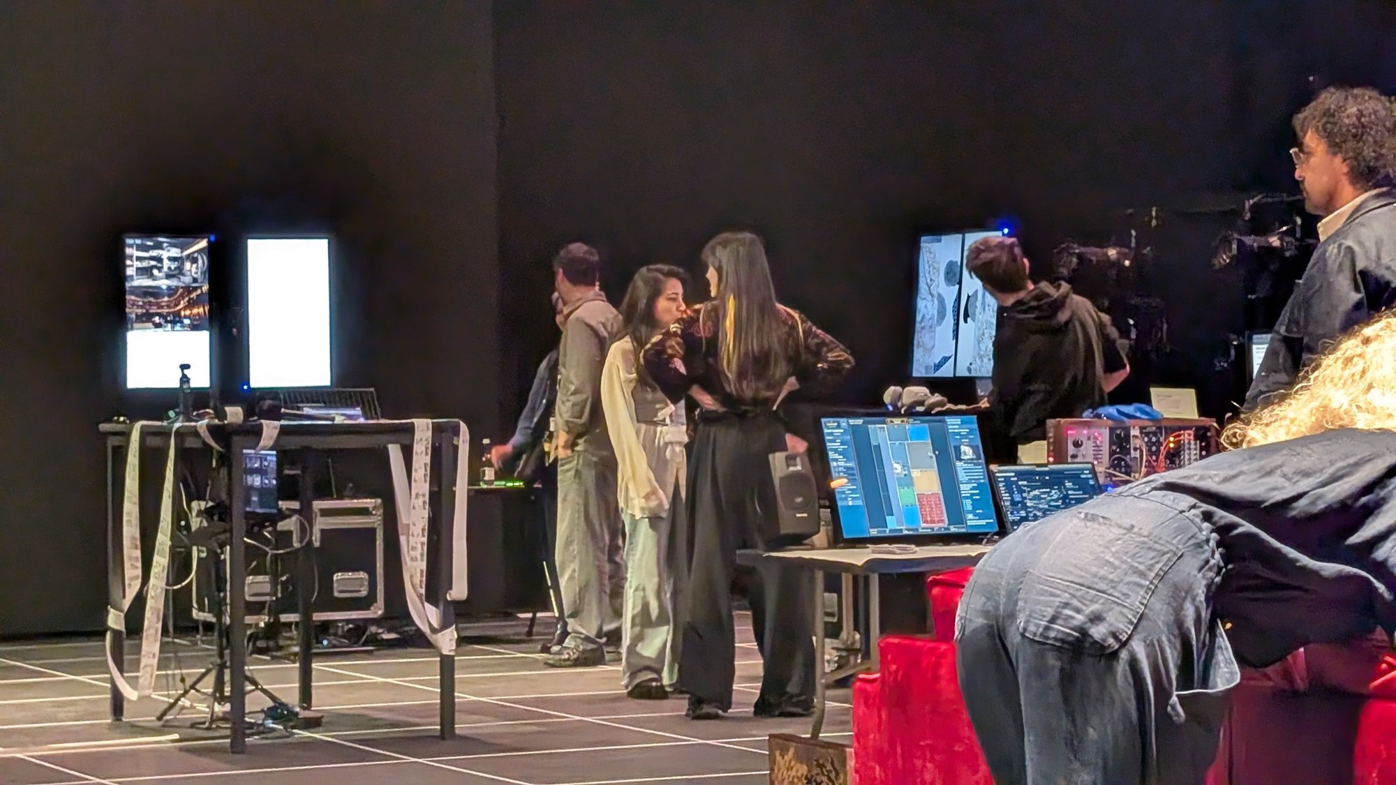 People gathered around laptops, monitors, and a sound setup during the public sharing.