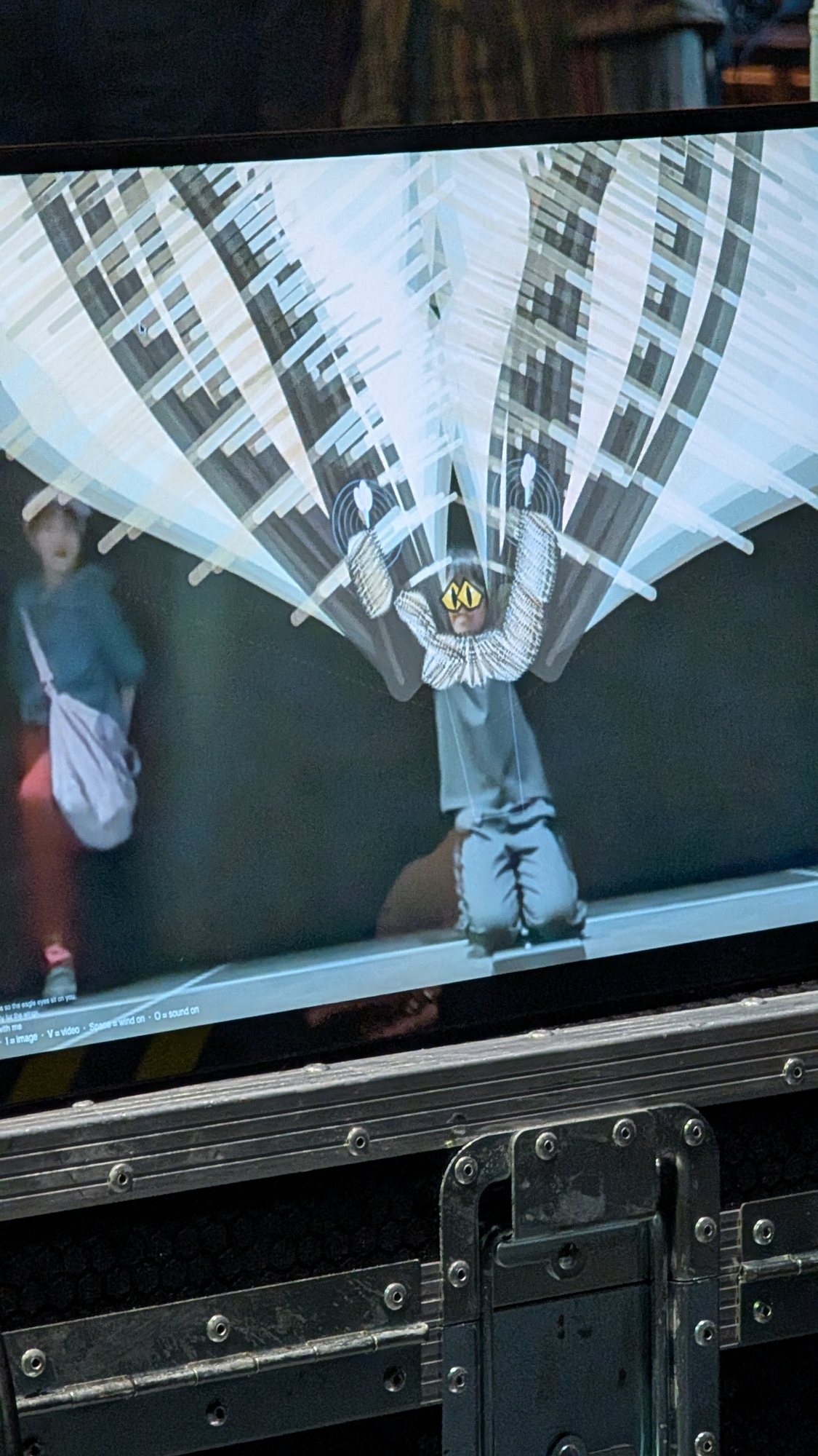 A close view of a monitor showing a kneeling figure with a fan of digital forms behind them.