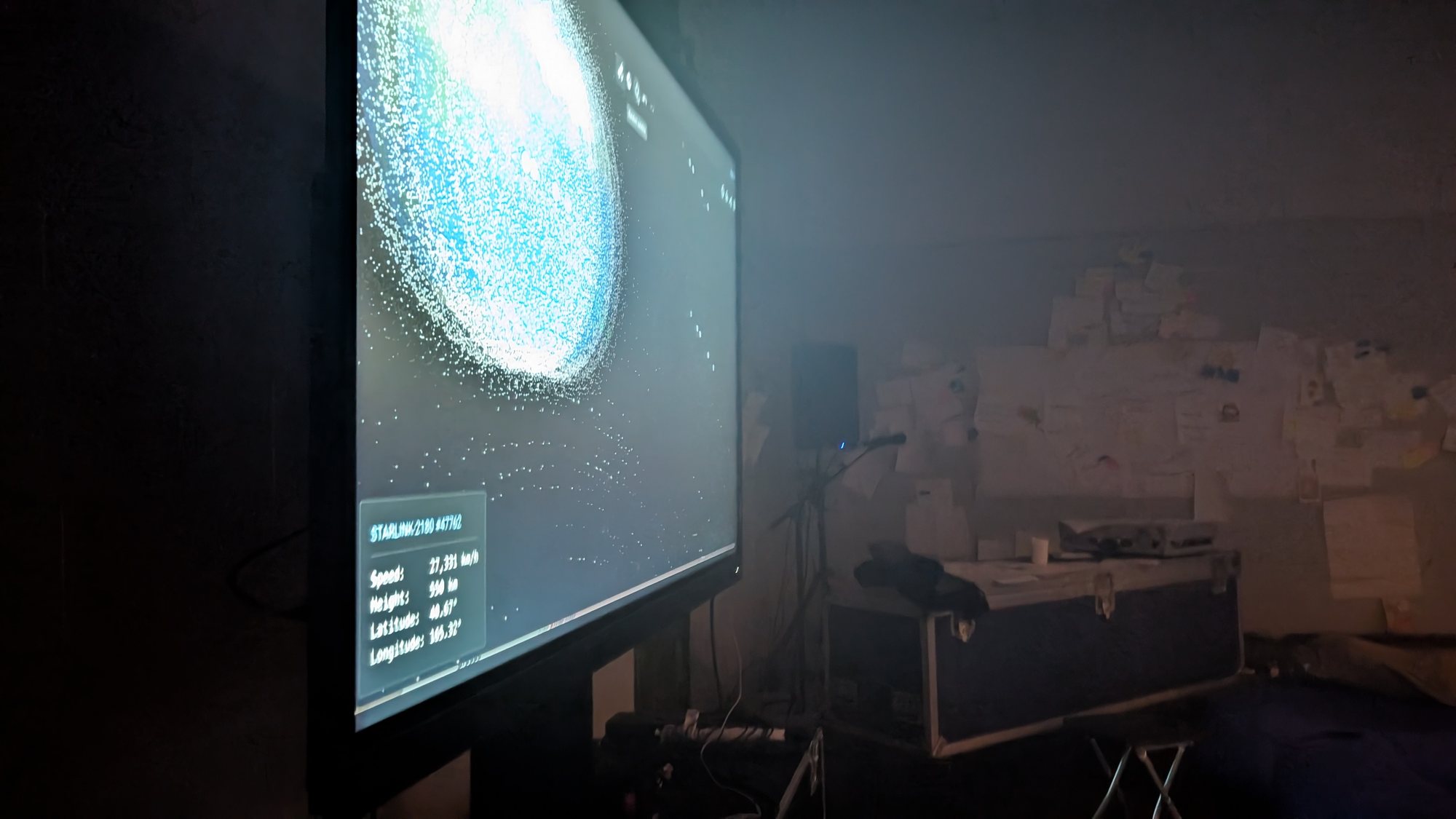 A projection of a satellite view of Earth fills a screen in the hazy installation.